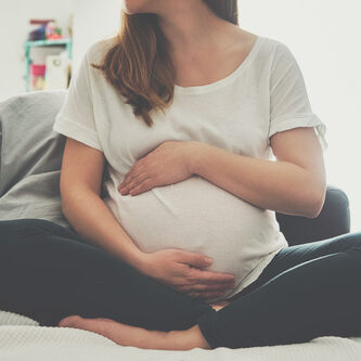 Gestational carrier sitting on bed | Fertility Specialists Medical Group | San Diego, CA