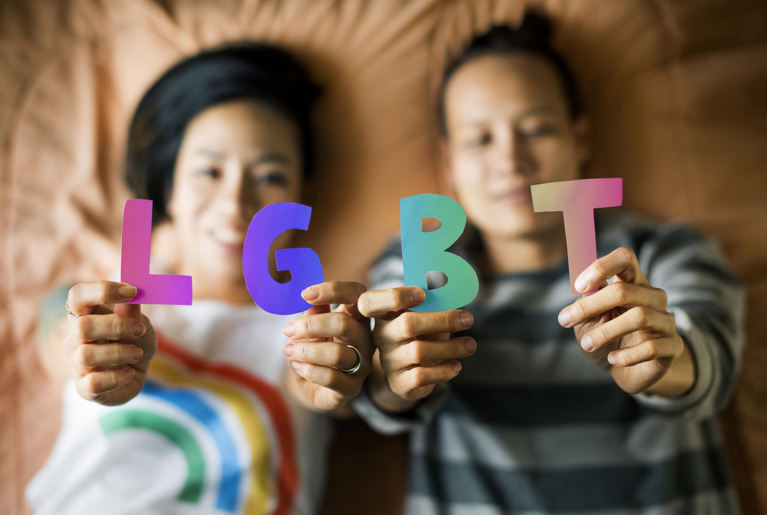 Lesbian couple pursuing parenthood via ROPE method celebrating with LGBT rainbow letters